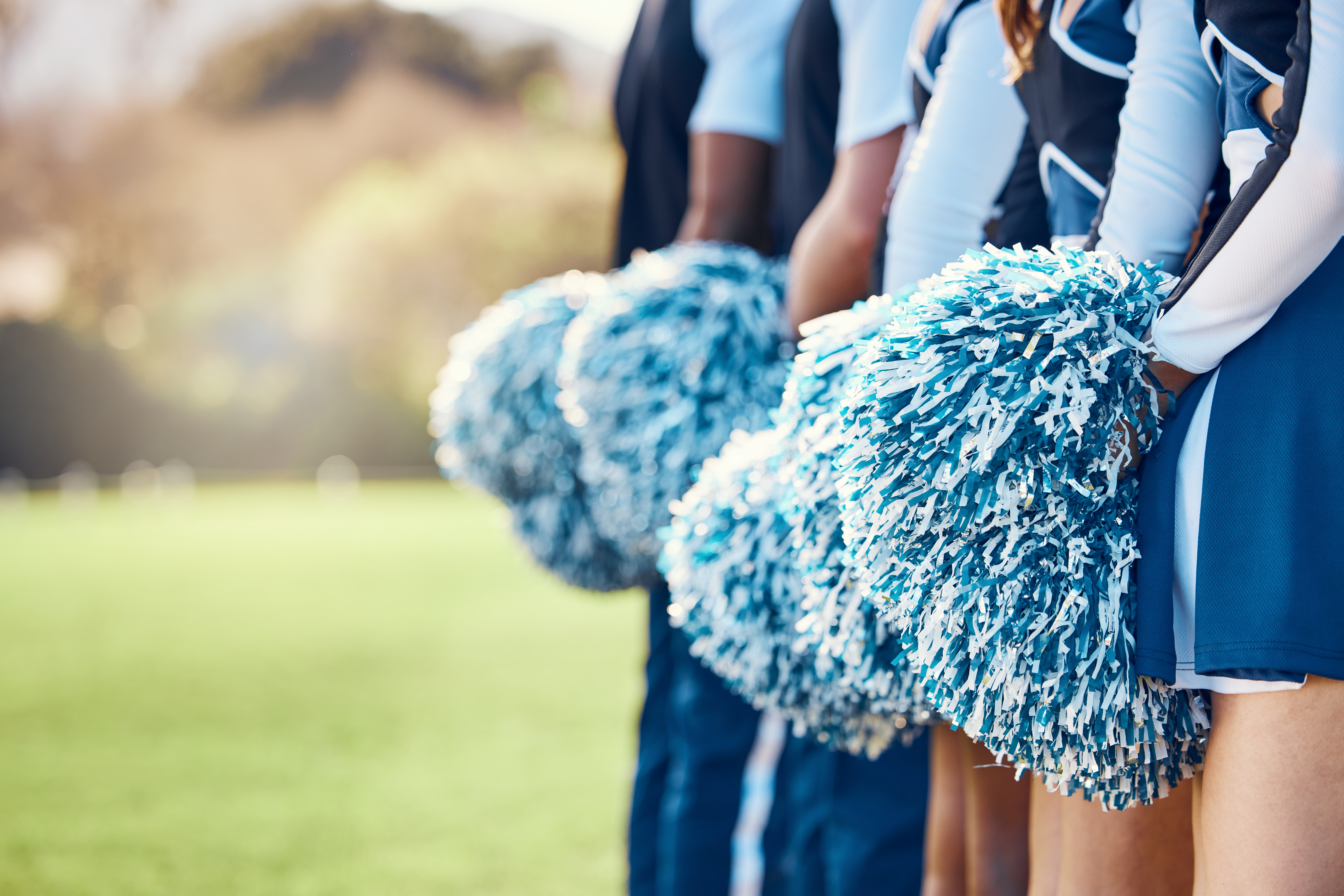 Cheerleaders in blue and white uniforms holding pom-poms on a field