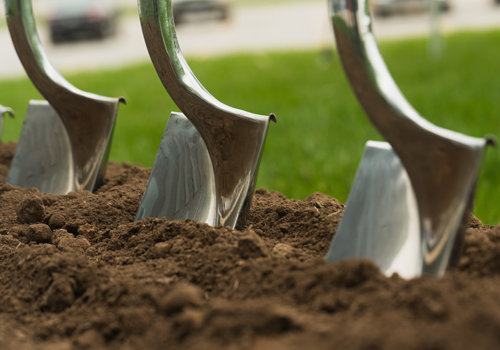 Three metal shovels in the dirt for a groundbreaking ceremony. 