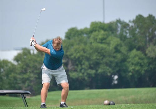 Hayden Delaloye swings his club on the tee box at a tournament.