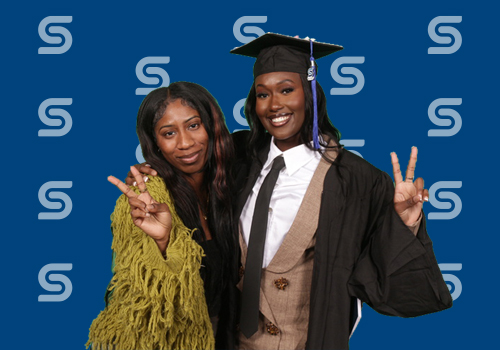 Two students pose for photos after the fall 2024 graduation ceremony. 